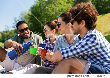 happy friends drinking tea from thermos in summer 59468940