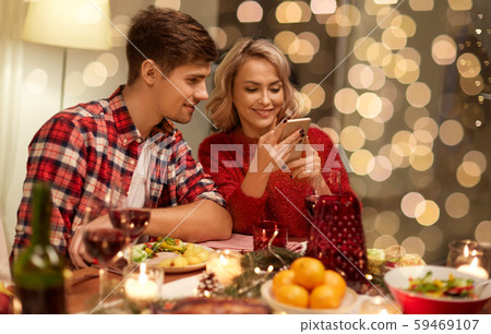 couple with smartphone at home christmas dinner couple with smartphone at home christmas dinner 59469107