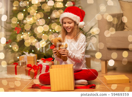 smiling girl in santa hat with christmas gift 59469359