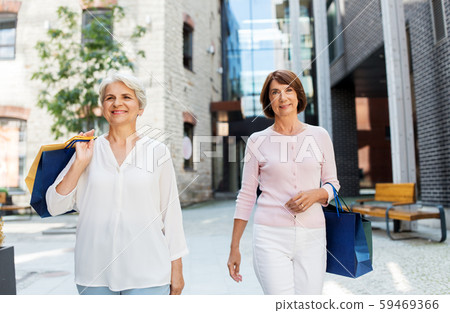 senior women with shopping bags walking in city 59469366