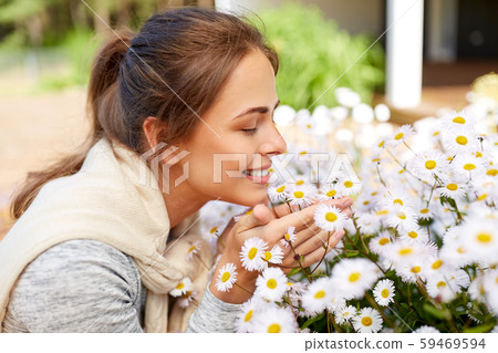 happy woman smelling chamomile flowers in garden 59469594