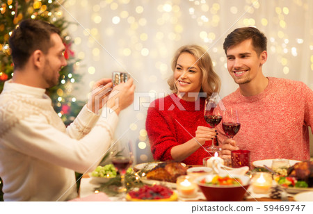 happy friends photographing at christmas dinner happy friends photographing at christmas dinner 59469747