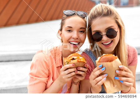teenage girls or friends eating burgers outdoors teenage girls or friends eating burgers outdoors 59469894