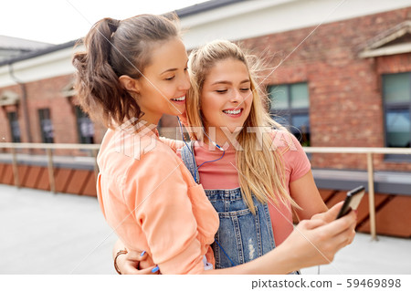 teenage girls listening to music on smartphone teenage girls listening to music on smartphone 59469898