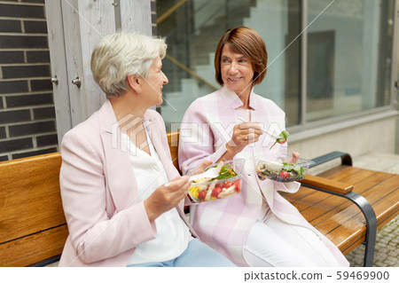 senior women eating takeaway food on city street senior women eating takeaway food on city street 59469900