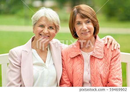 senior women or friends sitting on bench at park 59469902