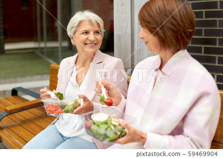 senior women eating takeaway food on city street 59469904