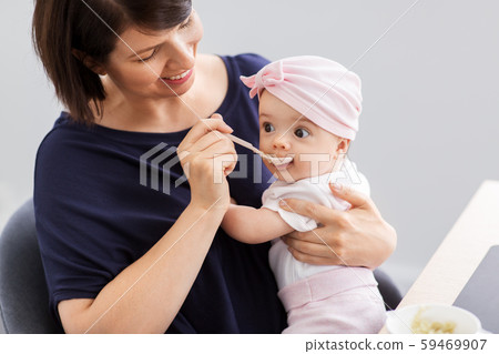 middle-aged mother feeding baby daughter at home middle-aged mother feeding baby daughter at home 59469907