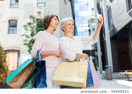 old women with shopping bags taking selfie in city old women with shopping bags taking selfie in city 59469931