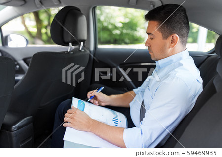 businessman with coffee on car back seat businessman with coffee on car back seat 59469935