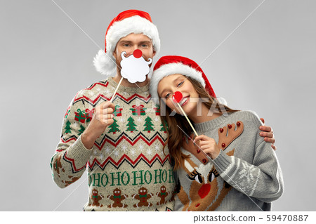 couple with christmas party props in ugly sweaters 59470887
