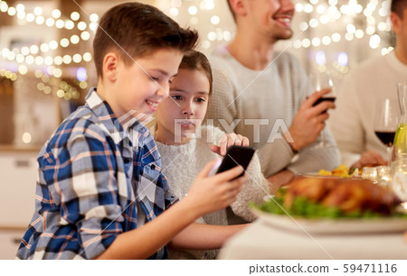 boy with sister using smartphone at family dinner 59471116