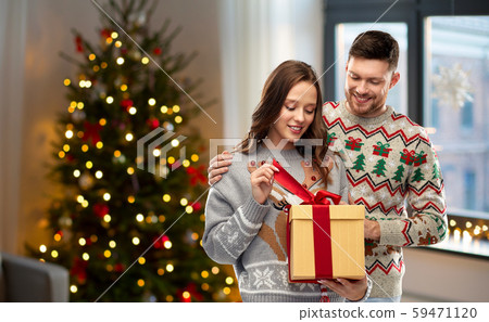 happy couple in christmas sweaters with gift box 59471120