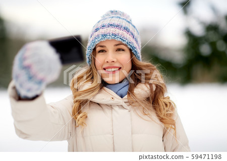 woman taking selfie by smartphone in winter woman taking selfie by smartphone in winter 59471198