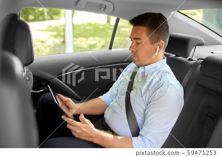 passenger with earphones and tablet pc in taxi car passenger with earphones and tablet pc in taxi car 59471253