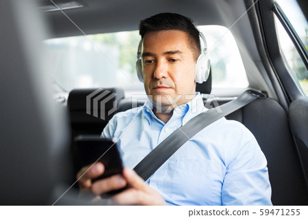 passenger with headphones using smartphone in car passenger with headphones using smartphone in car 59471255