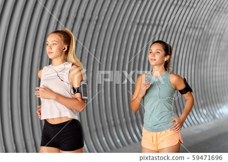 young women with earphones and smartphones running young women with earphones and smartphones running 59471696