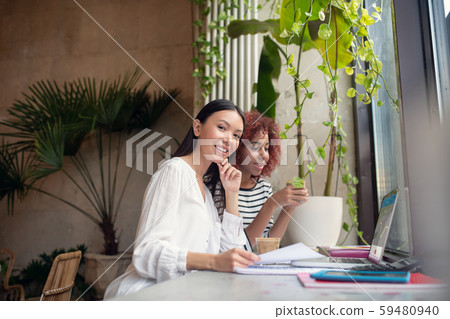 Two beautiful business partners sitting near laptop Two beautiful business partners sitting near laptop 59480940