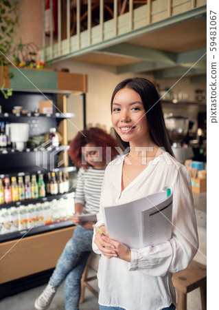 Asian woman owning cafeteria with friend holding documents 59481067
