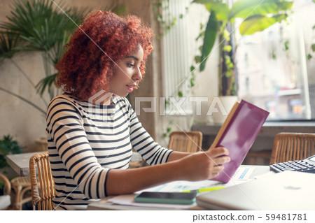 Red-haired young pretty businesswoman reading business literature Red-haired young pretty businesswoman reading business literature 59481781