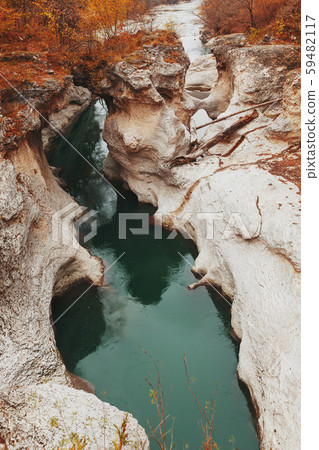 Gorge with a mountain river with a vibrant turquoise water between the rocks. Gorge with a mountain river with a vibrant turquoise water between the rocks. 59482117
