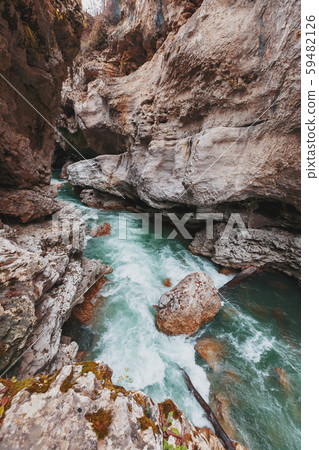 Gorge with a mountain river with a vibrant turquoise water between the rocks. 59482126