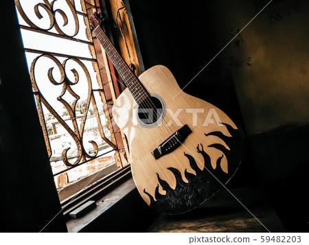 An acoustic guitar placed next to the old vintage window An acoustic guitar placed next to the old vintage window 59482203