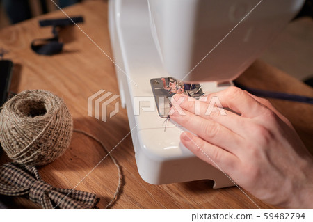 Tailor makes bow ties of woolen fabric. Work with sewing machine in a textile studio. Tailor makes bow ties of woolen fabric. Work with sewing machine in a textile studio. 59482794