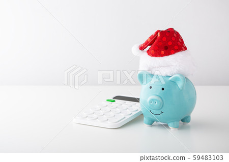 Piggy bank wearing christmas hat with calculator 59483103
