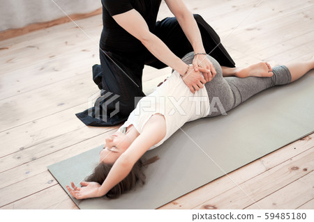 Sportswoman stretching on rug with male trainer on wooden floor 59485180