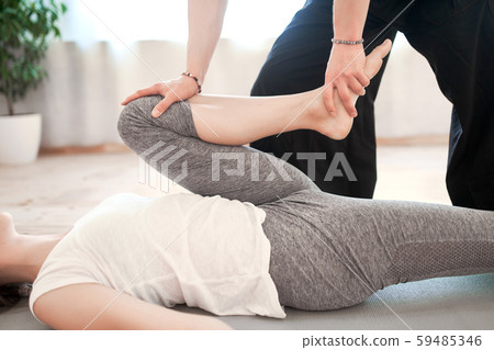 Man doing stretching exercises for woman while lying on gray rug in gym 59485346