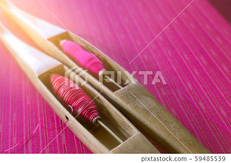 Pink yarn in weaving shuttle tool on traditional 59485539