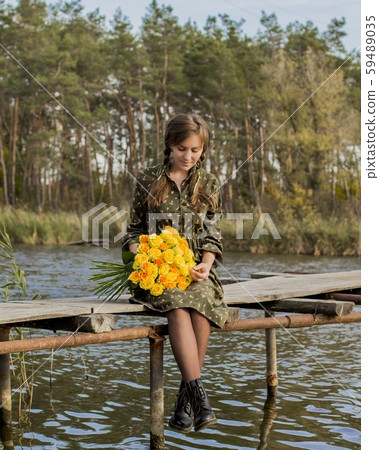Beautiful girl with a bouquet of yellow roses. Effective woman near the river. Pretty Woman. Teen girl with yellow roses. Girl on the old bridge. 59489035