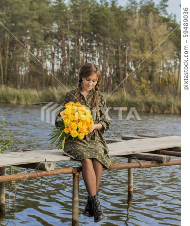 Beautiful girl with a bouquet of yellow roses. Effective woman near the river. Pretty Woman. Teen girl with yellow roses. Girl on the old bridge. 59489036