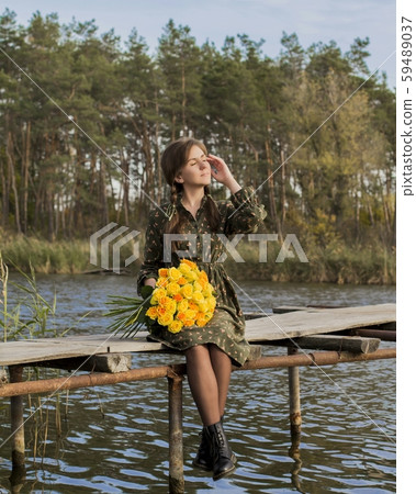 Beautiful girl with a bouquet of yellow roses. Effective woman near the river. Pretty Woman. Teen girl with yellow roses. Girl on the old bridge. 59489037