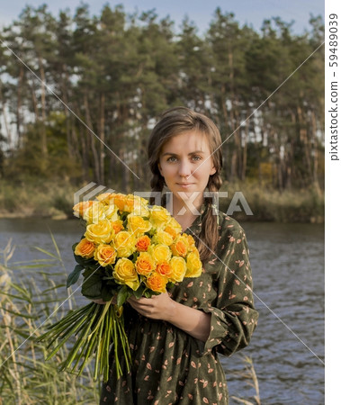 Beautiful girl with a bouquet of yellow roses. Effective woman near the river. Pretty Woman. Teen girl with yellow roses. 59489039