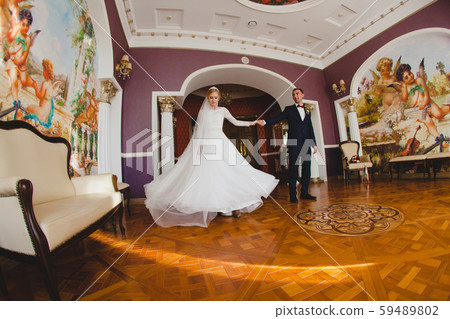 Bridegroom and his bride dancing on parquet floor in the big hall Bridegroom and his bride dancing on parquet floor in the big hall 59489802