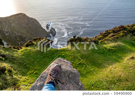 Feet trekking boots on rocky cliff edge 59490900