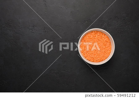 Bowl of lentils on a textured wooden black background. Vegetable protein healthy food 59491212