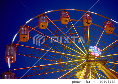 Illuminated ferris wheel in amusement park at a night city 59491518
