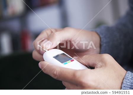 man about to measure his blood glucose level. 59491551