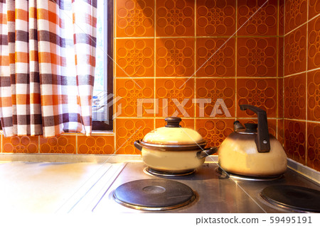 Original vintage kitchen of middle class with orange tiles and old stove with kitchen tools pans 59495191