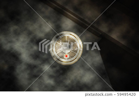 Smoke detector on the wall with red warning light sensor and smoke. fire concept house on fire