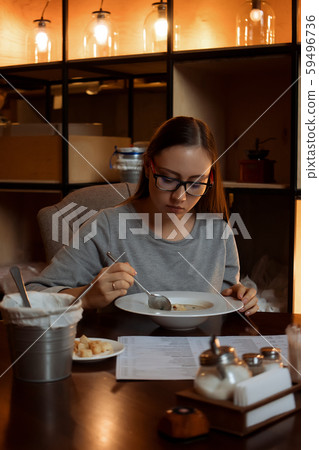Young woman eating soup in cafe 59496736