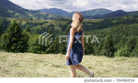 Woman standing on the mountain top looking at panoramic view of mountain range 59496834