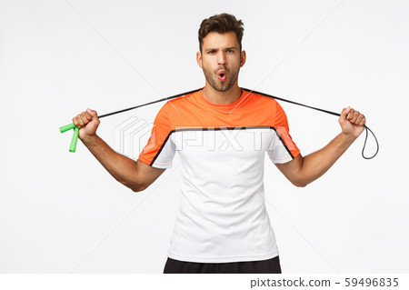 Handsome, energized sportsman ready for workout, hold jump rope behind neck, frowning sassy and look 59496835