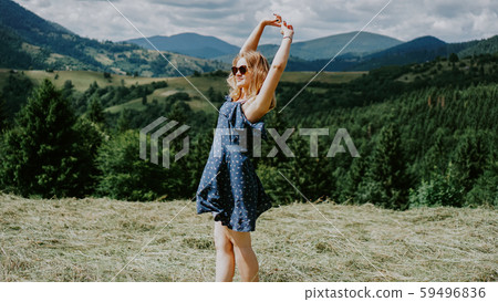 Woman standing on the mountain top looking at panoramic view of mountain range 59496836