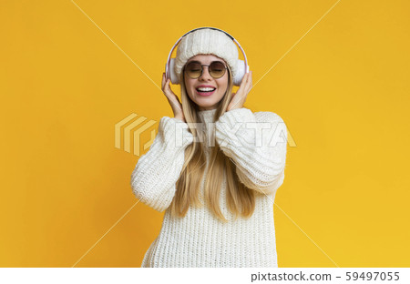 Winter girl in earphones posing over yellow studio background 59497055