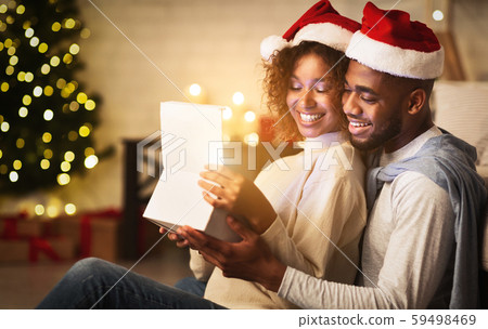 Xmas magic. Cute couple opening Christmas gift box 59498469