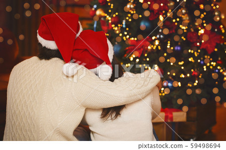 Happily married couple looking at Christmas tree, back view Happily married couple looking at Christmas tree, back view 59498694